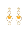 Goudkleurige oorhangers met een oker geel element in de hanger
